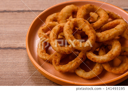 Deep fried breaded onion or squid rings, crispy fast food snacks. Fried onion or squid rings 141493195