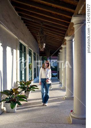 Woman Walking Through Covered Colonnade With White Columns Woman Walking Through Covered Colonnade With White Columns 141493677