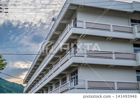 【#ElementarySchool】The exterior of the white school building against a backdrop of cloudy skies and mountains. 【#ElementarySchool】The exterior of the white school building against a backdrop of cloudy skies and mountains. 141493948