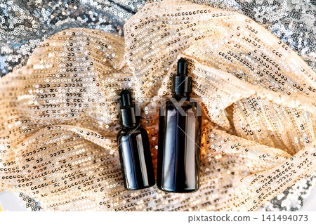 Luxury cosmetic oil dropper bottles on sparkling fabric 141494073