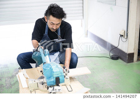 一位男性工匠正在使用滑動式斜切鋸進行木工和DIY項目,包括使用電動工具製作家具。 一位男性工匠正在使用滑動式斜切鋸進行木工和DIY項目,包括使用電動工具製作家具。 141494207