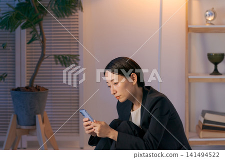 一個女人茫然地盯著她的智慧型手機 一個女人茫然地盯著她的智慧型手機 141494522