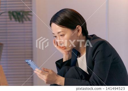 一個女人茫然地盯著她的智慧型手機 一個女人茫然地盯著她的智慧型手機 141494523