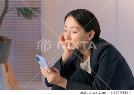 一個女人茫然地盯著她的智慧型手機 一個女人茫然地盯著她的智慧型手機 141494524