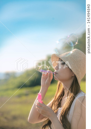 夏天，一位女士在水邊吹肥皂泡。 141494840