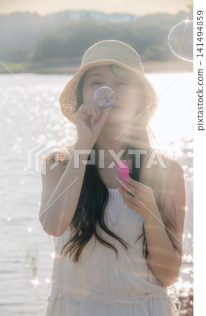 一位女子在閃爍的燈光下吹肥皂泡。 一位女子在閃爍的燈光下吹肥皂泡。 141494859