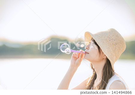 一位女子在夢幻般的燈光下吹著肥皂泡。 一位女子在夢幻般的燈光下吹著肥皂泡。 141494866