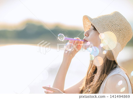 一位女士在夏日陽光下吹起肥皂泡。 一位女士在夏日陽光下吹起肥皂泡。 141494869