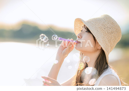 一位女子在閃爍的燈光下吹肥皂泡。 一位女子在閃爍的燈光下吹肥皂泡。 141494873