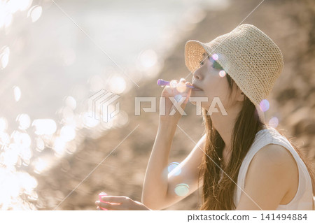 夏天,一位女士在水邊吹肥皂泡。 夏天,一位女士在水邊吹肥皂泡。 141494884