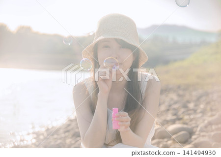 一位女士在夏日的陽光下吹起肥皂泡。 一位女士在夏日的陽光下吹起肥皂泡。 141494930