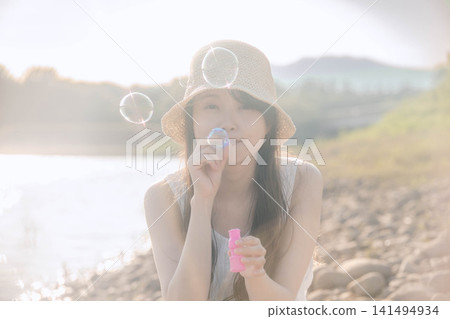 一位女士在夏日陽光下吹起肥皂泡。 一位女士在夏日陽光下吹起肥皂泡。 141494934