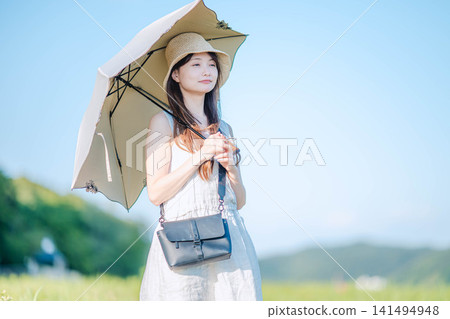一位女士在夏日草地上撐著陽傘，面帶微笑。 141494948