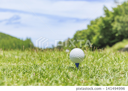 A white golf ball teed up on the teeing ground of a golf course. A white golf ball teed up on the teeing ground of a golf course. 141494996