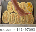 Top view many pieces of pan cake cooking on the metal pan with hand of chek holding the cutting tool. 141497093