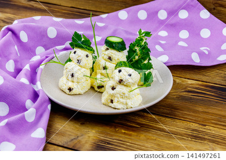 Christmas salad in the shape of snowmen and Christmas tree on a plate on wooden table Christmas salad in the shape of snowmen and Christmas tree on a plate on wooden table 141497261
