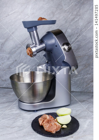 Electric eat grinder and fresh meat on kitchen table. Preparation of minced meat Electric eat grinder and fresh meat on kitchen table. Preparation of minced meat 141497285