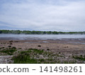 A quiet tidal flat stretches out under a cloudy sky. 141498261