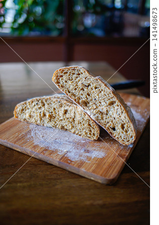 Close-up of sourdough artisan bread slices showing airy crumb and crust on wooden board. Rustic bakery and homemade food concept. Close-up of sourdough artisan bread slices showing airy crumb and crust on wooden board. Rustic bakery and homemade food concept. 141498673