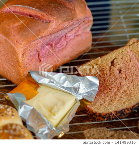 Fresh homemade pink marble bread with sliced loaf and butter arranged on a cooling rack. Rustic bakery scene featuring natural light, artisan baking, breakfast, and homemade food styling. 141499316