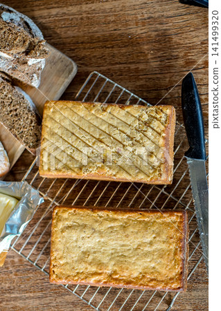 Fresh Homemade Loaf Cakes Cooling on Wire Rack with Rustic Bread Butter and Wooden Table Flat Lay 141499320