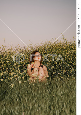 Woman flowers meadow sitting in a vibrant field of yellow mustard blossoms enjoying the peaceful spring sunshine during a quiet day Woman flowers meadow sitting in a vibrant field of yellow mustard blossoms enjoying the peaceful spring sunshine during a quiet day 141499328