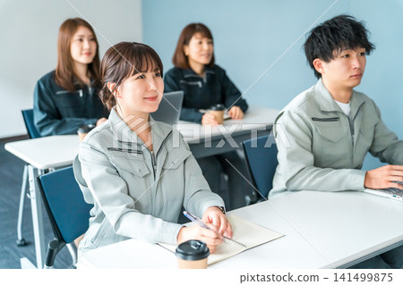 Businessmen and women in work clothes listening to a conference, meeting, or presentation Businessmen and women in work clothes listening to a conference, meeting, or presentation 141499875