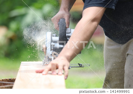 A man cutting lumber with a circular saw. A man cutting lumber with a circular saw. 141499991