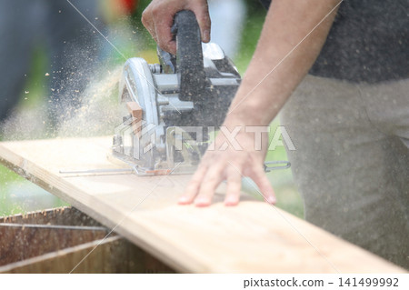 A man cutting lumber with a circular saw. A man cutting lumber with a circular saw. 141499992