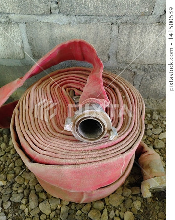 a roll of fire hose lying on the ground a roll of fire hose lying on the ground 141500539