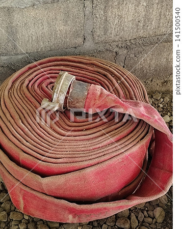a roll of fire hose lying on the ground a roll of fire hose lying on the ground 141500540