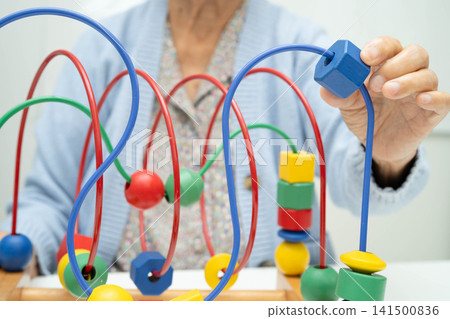 Asian elderly woman playing enhancing skill board game. Asian elderly woman playing enhancing skill board game. 141500836