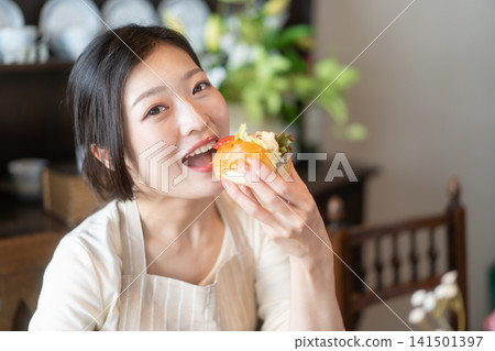A young woman eating a sandwich at a guesthouse in a traditional Japanese-style house. A young woman eating a sandwich at a guesthouse in a traditional Japanese-style house. 141501397