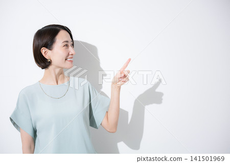 A Japanese woman in a short-sleeved top is shown smiling and pointing to give directions; this image is meant to convey information, points of interest, etc. 141501969