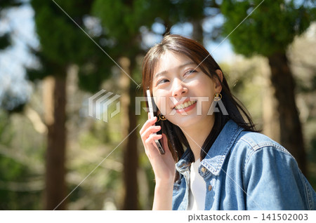 Japanese woman talking on the phone in a park 141502003