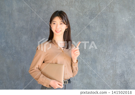 一位日本女商務人士手持筆記型電腦,指著前方。 一位日本女商務人士手持筆記型電腦,指著前方。 141502018
