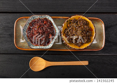 sichuan peppercorn sauce and savory beef paste in small dishes, twin spicy Asian condiments on a ceramic platter, top view. sichuan peppercorn sauce and savory beef paste in small dishes, twin spicy Asian condiments on a ceramic platter, top view. 141502245