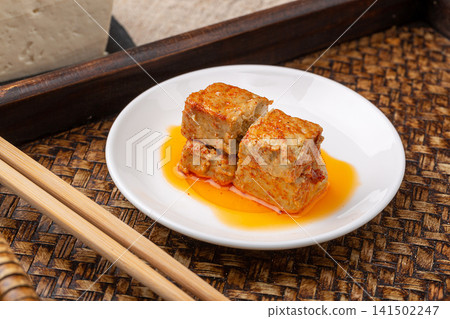 fermented bean curd in spicy chili oil, traditional Chinese sufu or chaozhou tofu on a white plate, gourmet Asian snack. fermented bean curd in spicy chili oil, traditional Chinese sufu or chaozhou tofu on a white plate, gourmet Asian snack. 141502247