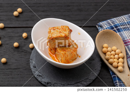 fermented bean curd in spicy chili oil, traditional Chinese sufu or chaozhou tofu on a white plate, gourmet Asian snack. fermented bean curd in spicy chili oil, traditional Chinese sufu or chaozhou tofu on a white plate, gourmet Asian snack. 141502250