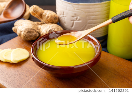 concentrated ginger juice pouring, pure aromatic yellow herbal extract for culinary seasoning and healthy beverages. concentrated ginger juice pouring, pure aromatic yellow herbal extract for culinary seasoning and healthy beverages. 141502291
