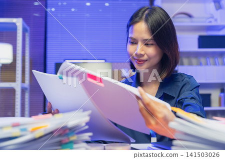 Young Asian businesswoman reviewing documents while working in office Young Asian businesswoman reviewing documents while working in office 141503026