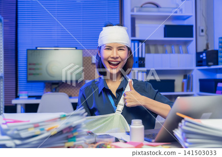 Injured young Asian businesswoman showing thumbs up while recovering at office Injured young Asian businesswoman showing thumbs up while recovering at office 141503033