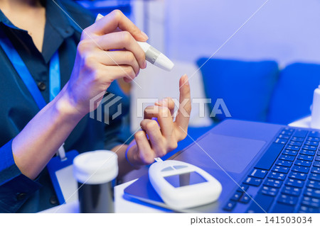 Young Asian woman checking blood sugar level with glucose meter Young Asian woman checking blood sugar level with glucose meter 141503034