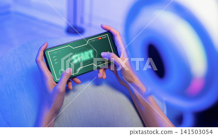 Girl playing mobile game on smartphone with gaming headset, online gaming and digital entertainment. Girl playing mobile game on smartphone with gaming headset, online gaming and digital entertainment. 141503054