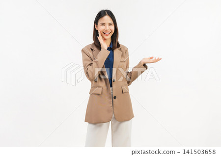 Smiling young Asian businesswoman presenting empty space with open palm and cheerful expression isolated on white background. 141503658