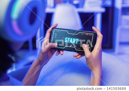 Girl playing mobile game on smartphone with gaming headset, online gaming and digital entertainment concept. Girl playing mobile game on smartphone with gaming headset, online gaming and digital entertainment concept. 141503689
