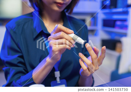 Young Asian woman checking blood sugar level with glucose meter, diabetes monitoring and healthcare concept. Young Asian woman checking blood sugar level with glucose meter, diabetes monitoring and healthcare concept. 141503730