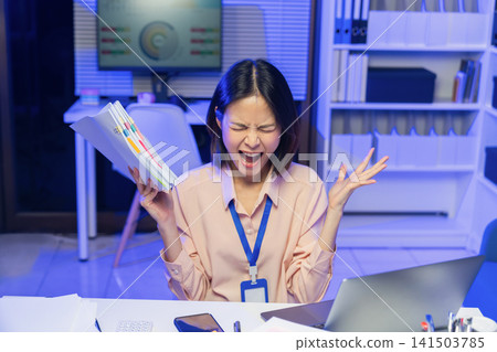 Stressed young Asian businesswoman overwhelmed with workload and holding documents while screaming in office. Stressed young Asian businesswoman overwhelmed with workload and holding documents while screaming in office. 141503785