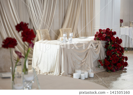 Elegant wedding reception table decorated with red roses and white candles Elegant wedding reception table decorated with red roses and white candles 141505160