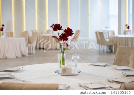 Elegant wedding reception table setting with red flowers and soft lighting Elegant wedding reception table setting with red flowers and soft lighting 141505165